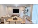 Bright and airy living room featuring an L-shaped couch, large windows, modern decor, and wood-style floors at 320 Lawrence Gray Rd, Charlotte, NC 28262