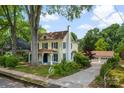 Quaint two-story yellow home with mature trees, a detached garage and driveway, and a well-manicured lawn at 522 Alexander St, Statesville, NC 28677