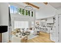 Open-concept living room with large windows, hardwood floors, modern furnishings, and seamless kitchen access at 621 Poindexter Dr, Charlotte, NC 28209
