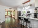 Bright kitchen featuring white cabinetry, marble countertops, and a breakfast bar leading into the living room at 9300 Surrey Rd, Mint Hill, NC 28227