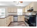 Well-lit kitchen featuring light wood cabinets, modern appliances, and laminate wood flooring at 10945 Wiltshire Ln, Charlotte, NC 28262