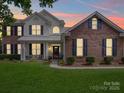 Charming two-story home with a well-manicured lawn and a welcoming front porch with black shutters at dusk at 1109 Woodwinds Dr, Waxhaw, NC 28173