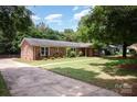 Brick home with mature landscaping and a concrete driveway, surrounded by lush greenery at 418 Melody Ln, Shelby, NC 28152