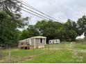 Exterior of mobile home with new deck, surrounded by green trees and a chain-link fence at 4417 Grier St, Gastonia, NC 28056