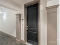 Modern black front door with elegant trim in a neutral-colored hallway at 4620 Piedmont Row Dr # 308, Charlotte, NC 28210