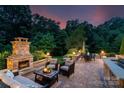 Relaxing brick patio featuring an outdoor fireplace, comfortable seating, dining table, and lush landscaping at 5044 Dockside Ct, Matthews, NC 28104