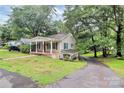 A quaint home with a covered porch, lush landscaping and tree coverage at 613 N Rhyne St, Gastonia, NC 28054