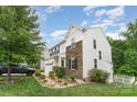 A two-story home featuring a white exterior with stone accents, a well-maintained lawn, and blue skies at 6726 Carradale Way, Charlotte, NC 28278