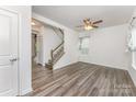 Spacious living room featuring wood-look floors, a staircase, and ample natural light through the windows at 6726 Carradale Way, Charlotte, NC 28278