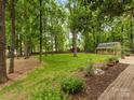 Lush backyard with mature trees and brick-paved patio at 8201 Lansford Rd, Charlotte, NC 28277