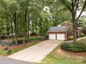 Long driveway leading to a two-car garage surrounded by lush trees at 8201 Lansford Rd, Charlotte, NC 28277