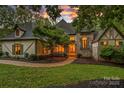 Charming front exterior with stone accents, lush landscaping, and a welcoming arched entryway at dusk at 10300 Sweetleaf Pl, Charlotte, NC 28278