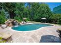 Inviting backyard pool with a rock waterfall feature surrounded by travertine tile at 1085 Wessington Manor Ln, Fort Mill, SC 29715
