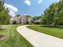 Beautifully landscaped lawn leads to this impressive brick home with mature trees and a long driveway at 1509 Churchill Downs Dr, Waxhaw, NC 28173