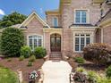Inviting entryway with a charming brick facade, manicured landscaping, and a grand wooden door at 1509 Churchill Downs Dr, Waxhaw, NC 28173