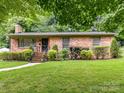 Charming brick home featuring a well-manicured lawn and lush landscaping at 1638 Wensley Dr, Charlotte, NC 28210
