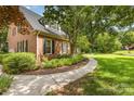 Landscaped side view featuring a charming walkway and the home's brick exterior with black shutters at 1750 Trellis Dr, Rock Hill, SC 29732
