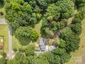 Expansive wooded property with a brick home featuring a metal roof, complemented by a convenient detached garage at 2320 Doster Rd, Monroe, NC 28112