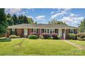 Charming one-story brick home with a lush green lawn and mature landscaping at 300 Caldwell St, Kannapolis, NC 28083