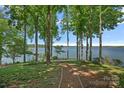 Serene backyard with a path leading to the lake, shaded by mature trees offering privacy and tranquility at 392 Stonemarker Rd, Mooresville, NC 28117