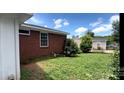 View of backyard with brick exterior, partial shed and luscious green grass at 4414 Birkdale Dr, Charlotte, NC 28208