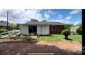 View of backyard with white siding, brick exterior, partial shed and luscious green grass at 4414 Birkdale Dr, Charlotte, NC 28208