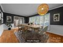 Bright dining room with hardwood floors, large windows, modern lighting, and elegant staging at 6017 Sierra Dr, Charlotte, NC 28216