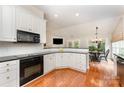 Bright, open kitchen with white cabinets, hardwood floors, and modern appliances flowing into the breakfast area at 7211 Baniff Cir, Charlotte, NC 28277