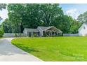 Landscaped front lawn with gray home, driveway, and wooden fence along the property line at 7901 Reames Rd, Charlotte, NC 28216
