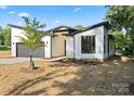Modern home with sleek garage door, black trim, minimalist landscaping, and a healthy growing young tree at 8632 Cedarbrook Dr, Charlotte, NC 28215
