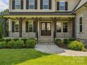 Welcoming front porch with dark wood posts and iron railing at 1008 Ladera Dr, Waxhaw, NC 28173