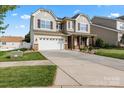 Attractive two-story home with an inviting front porch and long driveway leading to a two-car garage at 112 Artisan Ct, Mooresville, NC 28117