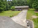 View of the house, with a long driveway leading to an attached garage and a cozy front porch with well-kept grounds at 1142 Foxberry Rd, Lincolnton, NC 28092