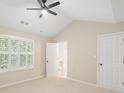 Neutral bedroom with vaulted ceiling, bright window with white shutters and view to an ensuite bathroom at 18840 Silver Quay Dr # 12, Cornelius, NC 28031
