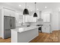 Modern kitchen features stainless steel appliances, white cabinetry, large island with quartz countertop at 2004 St John St, Charlotte, NC 28216