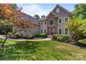 Stunning home showcasing a stone facade, manicured lawn, mature landscaping and a charming walkway leading to the front door at 2006 Sandy Pond Ln, Waxhaw, NC 28173