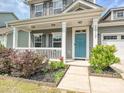 Inviting front porch featuring a blue door, white columns, and manicured landscaping at 2017 New Hope Branch Way, Belmont, NC 28012