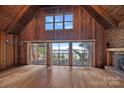 Spacious living room with wood-paneled walls, high ceilings, fireplace, and lake view through sliding doors at 2563 Brawley School Rd, Mooresville, NC 28117