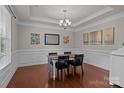 Formal dining room featuring hardwood floors, tray ceiling, and elegant wainscoting at 4117 Bright Rd, Charlotte, NC 28214