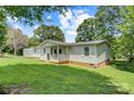 View of the house from the rear showing a side porch and lawn with mature trees and blue sky at 4648 Rifle Range Rd, Conover, NC 28613