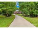 Long driveway leading to a beautiful two-story brick home, surrounded by lush trees and a well-manicured lawn at 763 Evans Manor Dr, Weddington, NC 28104