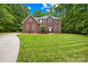 Spacious two-story brick home on a sprawling green lawn, surrounded by mature trees, offering a serene setting at 763 Evans Manor Dr, Weddington, NC 28104