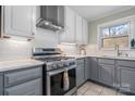Modern kitchen with a stainless steel gas range, subway tile backsplash, and gray cabinets under a bright window at 1525 16Th Avenue Nw Cir, Hickory, NC 28601