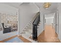 Elegant staircase featuring hardwood floors, a carpet runner, and designer light fixture at 1625 Bibury Ln, Charlotte, NC 28211