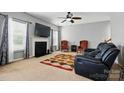 Cozy living room with a fireplace, ceiling fan, and comfortable seating arrangement with warm natural light at 2324 Oakdale Creek Ln, Charlotte, NC 28216