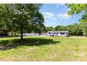 Serene view of a home with a large grassy area, complemented by mature trees and a white fence at 4750 Enochville Rd, Kannapolis, NC 28081