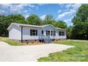 A well-maintained single-story home with gray siding, dark shutters, and a gravel driveway at 4750 Enochville Rd, Kannapolis, NC 28081