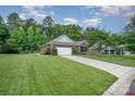 Well-maintained home with lush lawn, mature trees, and long driveway leading to a two-car garage at 8737 Mullis Forest Ct, Mint Hill, NC 28227