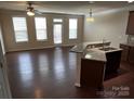 Open-concept living room with hardwood floors, ceiling fan, and breakfast bar overlooking kitchen at 9593 Camberley Nw Ave, Concord, NC 28027