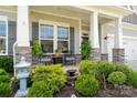 Inviting front porch with stone accents, elegant seating, and lush landscaping with a tranquil fountain at 10016 St Kitts Landing Ln, Charlotte, NC 28278